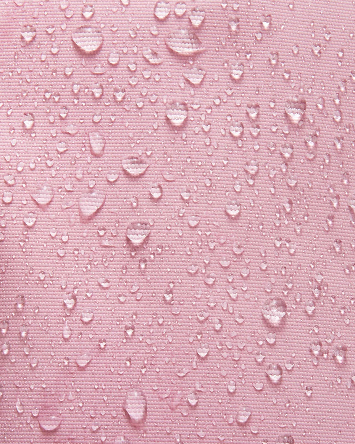 Close-up shot demonstrating the water and dirt repellent technology on the grey pink Reima Tassuin toddler mittens, with multiple water droplets beading on the woven fabric surface.