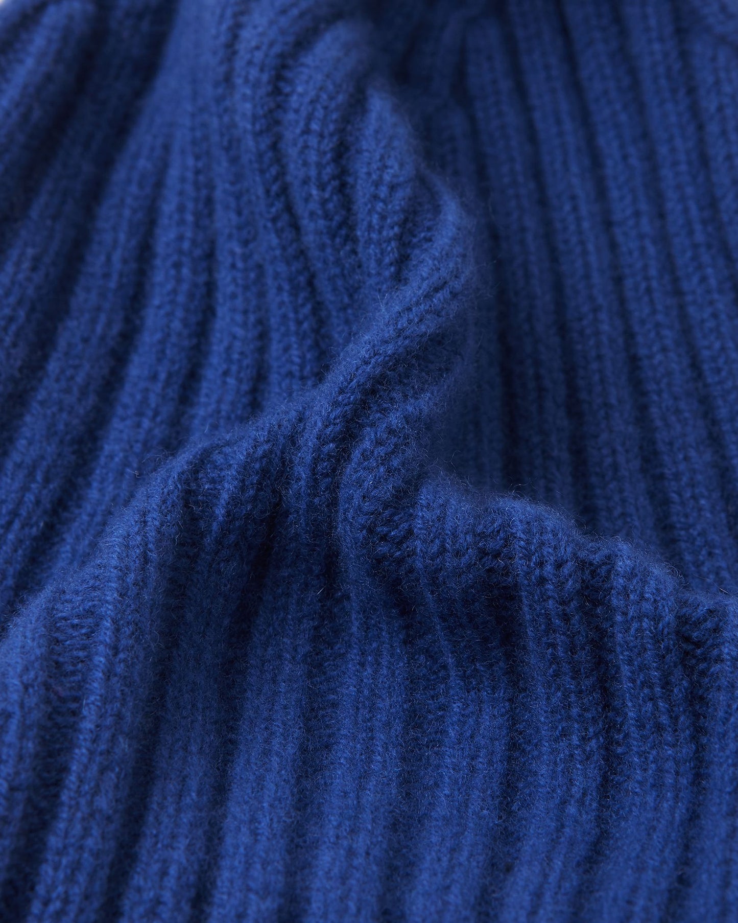 Macro close-up of the thick, vertical ribbed knit structure on the twilight blue Reima Topsu kids' winter hat, demonstrating the high-quality texture, stretch, and flexibility of the warm wool-blend yarn.