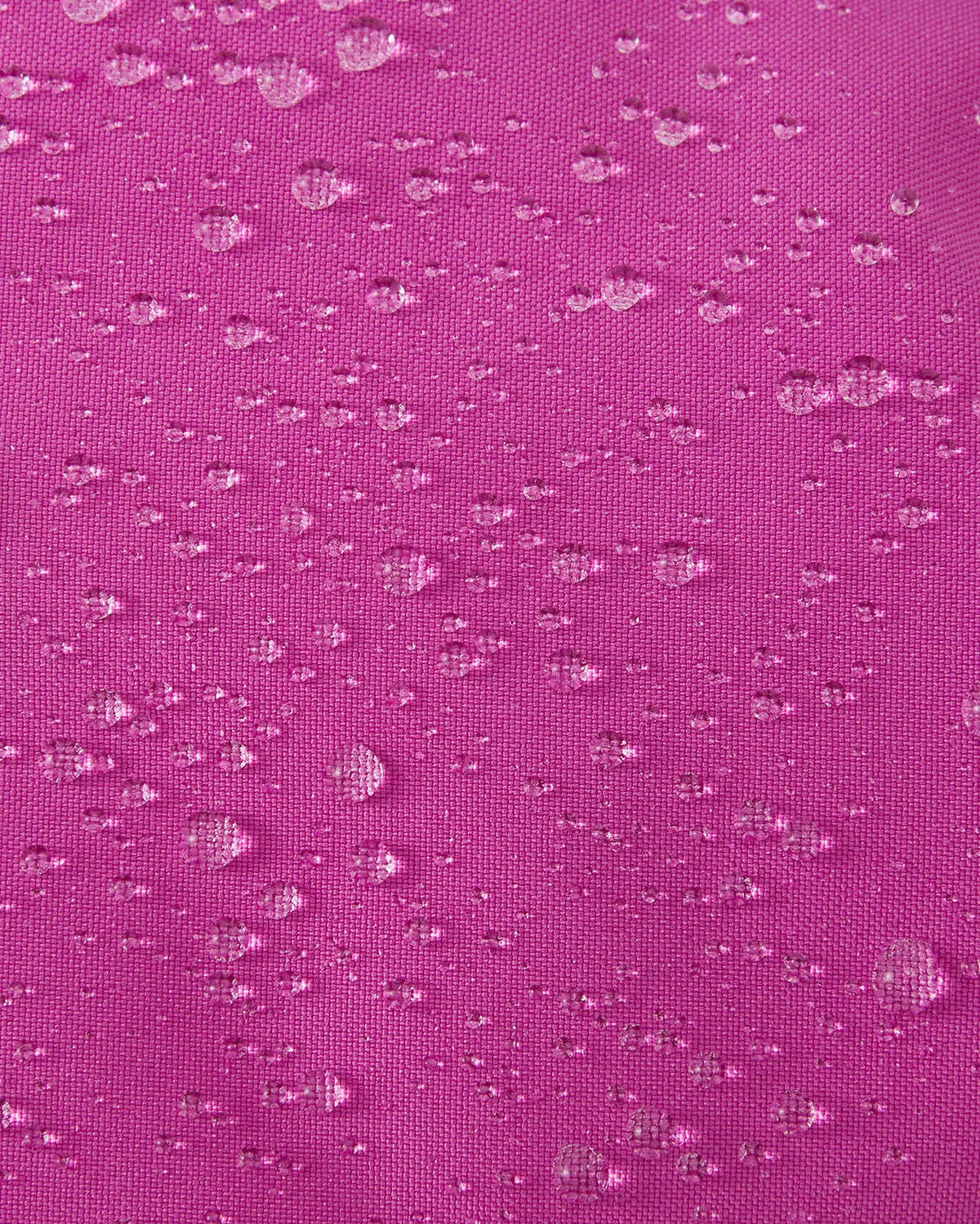 A macro close-up of the woven fuchsia fabric used on the Reima Vanukko kids' ski mittens, showing multiple water droplets beading on the surface to demonstrate its waterproof and dirt-repellent finish.