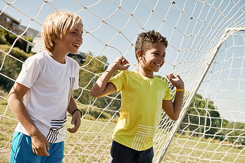 The boys are standing in a soccer net.