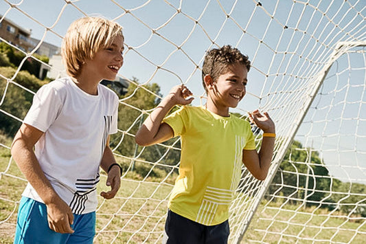 The boys are standing in a soccer net.