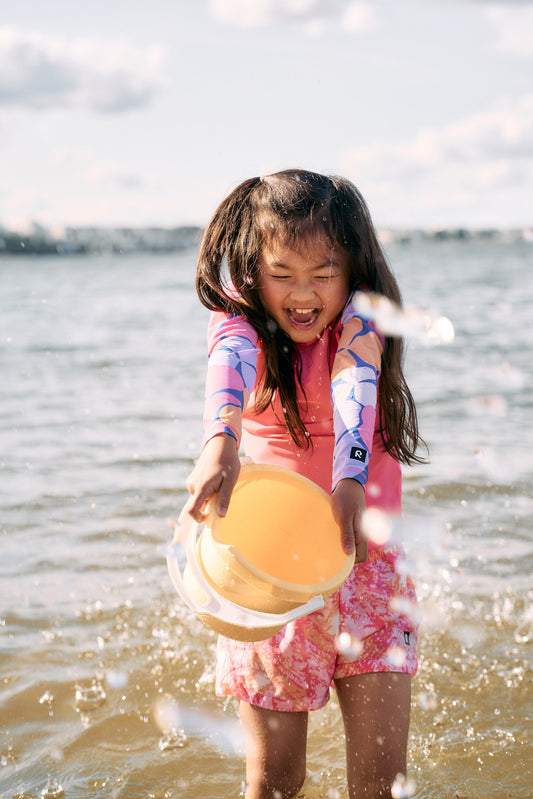 The girl is pouring the water out of the bucket.