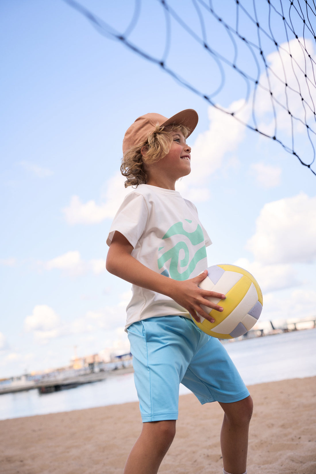 The kid is holding a volleyball.