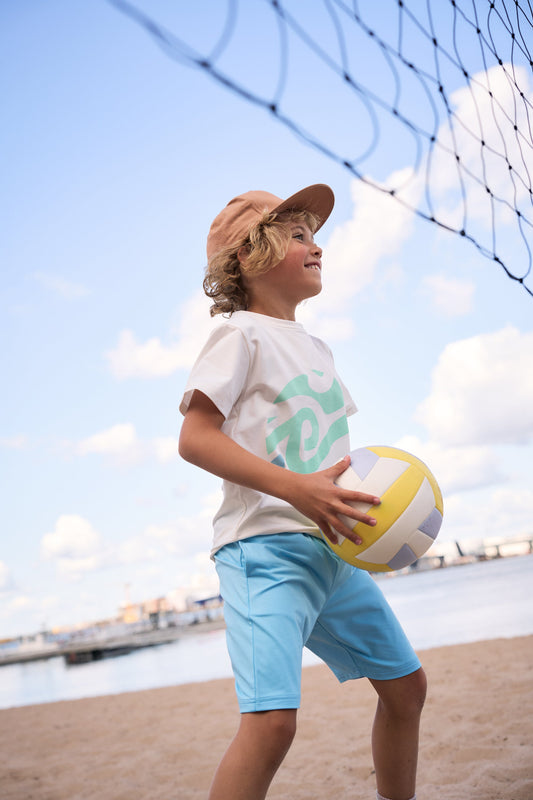 The kid is holding a volleyball.