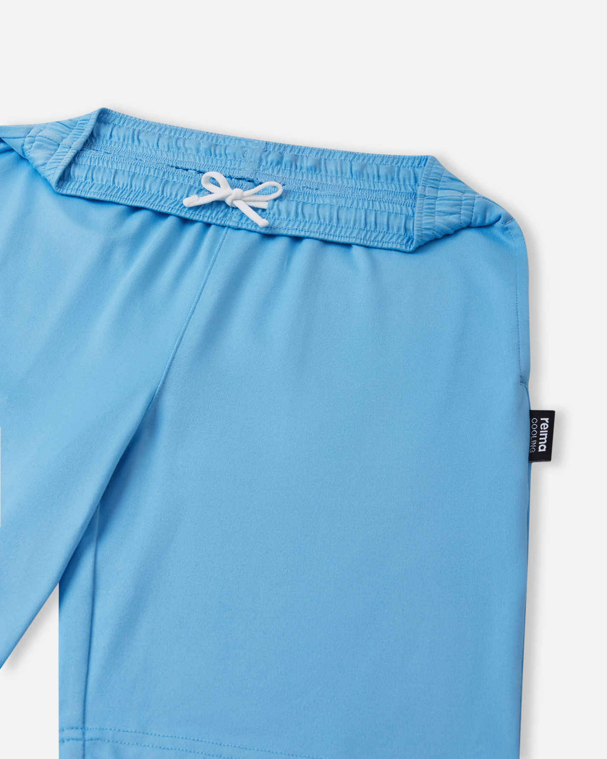 A close-up view of the gathered elastic waistband and white adjustable drawstring on the light blue Reima Ilmasa shorts. A small black Reima logo tag is visible on the side seam.