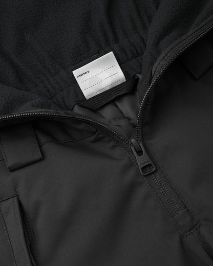 Interior detail view of the black Reima Alppi kids' snow bibs, featuring a customizable blank name tag label inside the soft fleece upper vest for easy identification at ski school or winter camp.
