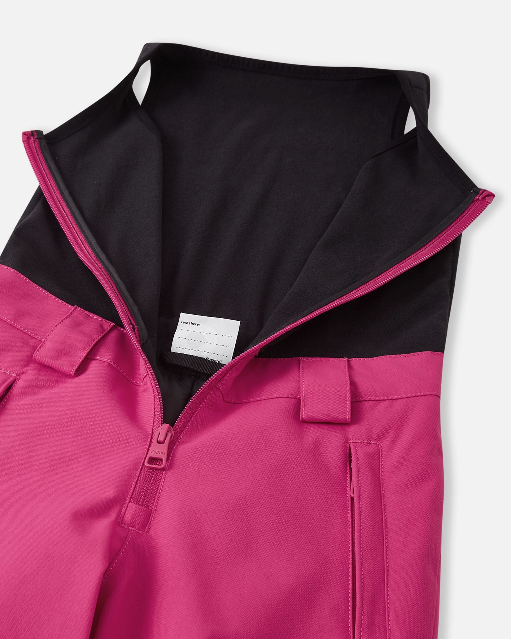 Close-up of the front zipper on the rosy berry Reima Alppi kids' snow bibs, revealing the cozy black fleece upper vest designed to provide extra core warmth and prevent drafts during winter play.