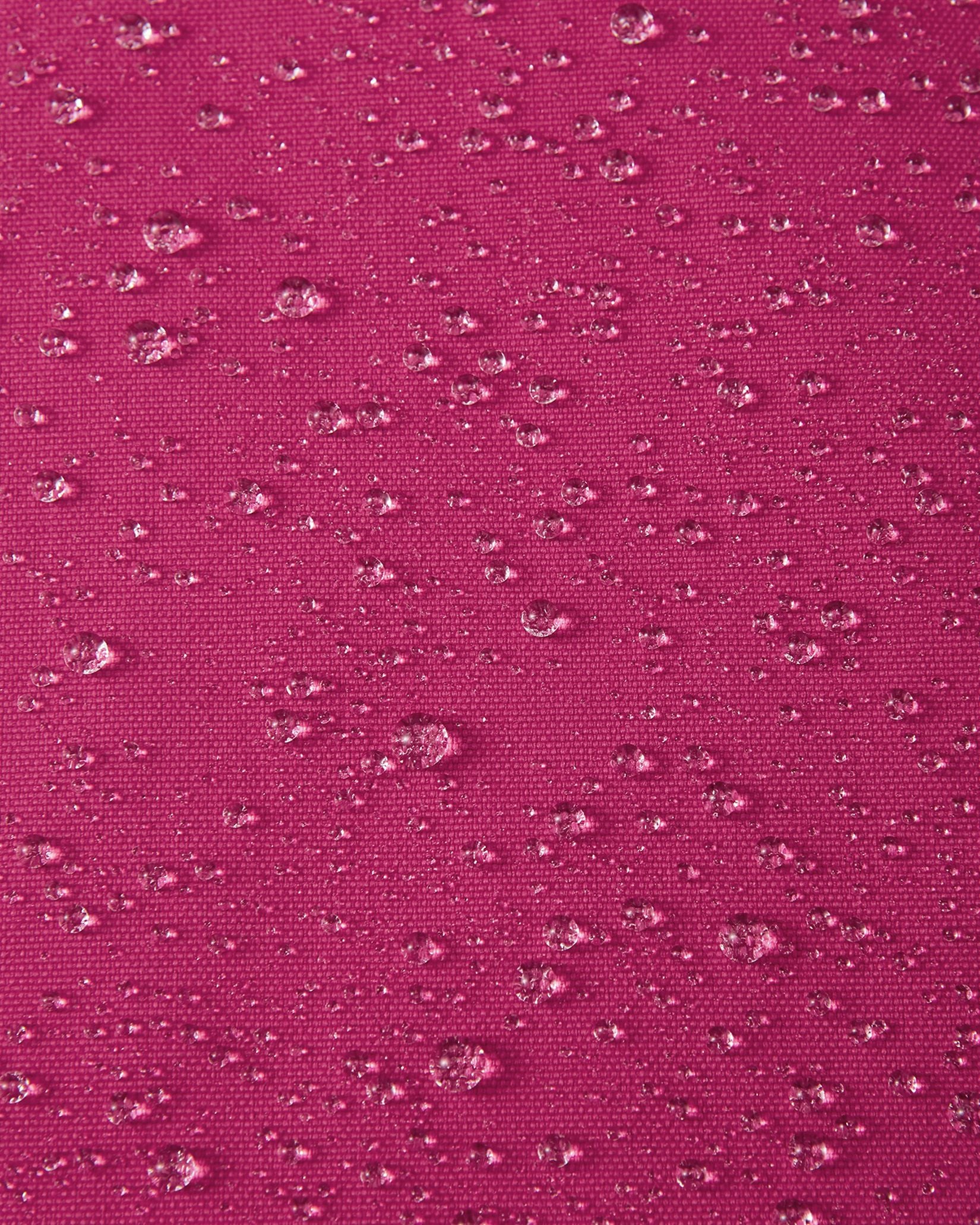 Macro close-up of water droplets actively beading and rolling off the rosy berry pink outer shell of the Reima Alppi kids' snow bibs, demonstrating the highly effective Reimatec waterproof and breathable membrane.