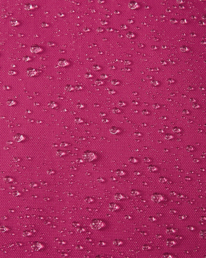 Macro close-up of water droplets actively beading and rolling off the rosy berry pink outer shell of the Reima Alppi kids' snow bibs, demonstrating the highly effective Reimatec waterproof and breathable membrane.