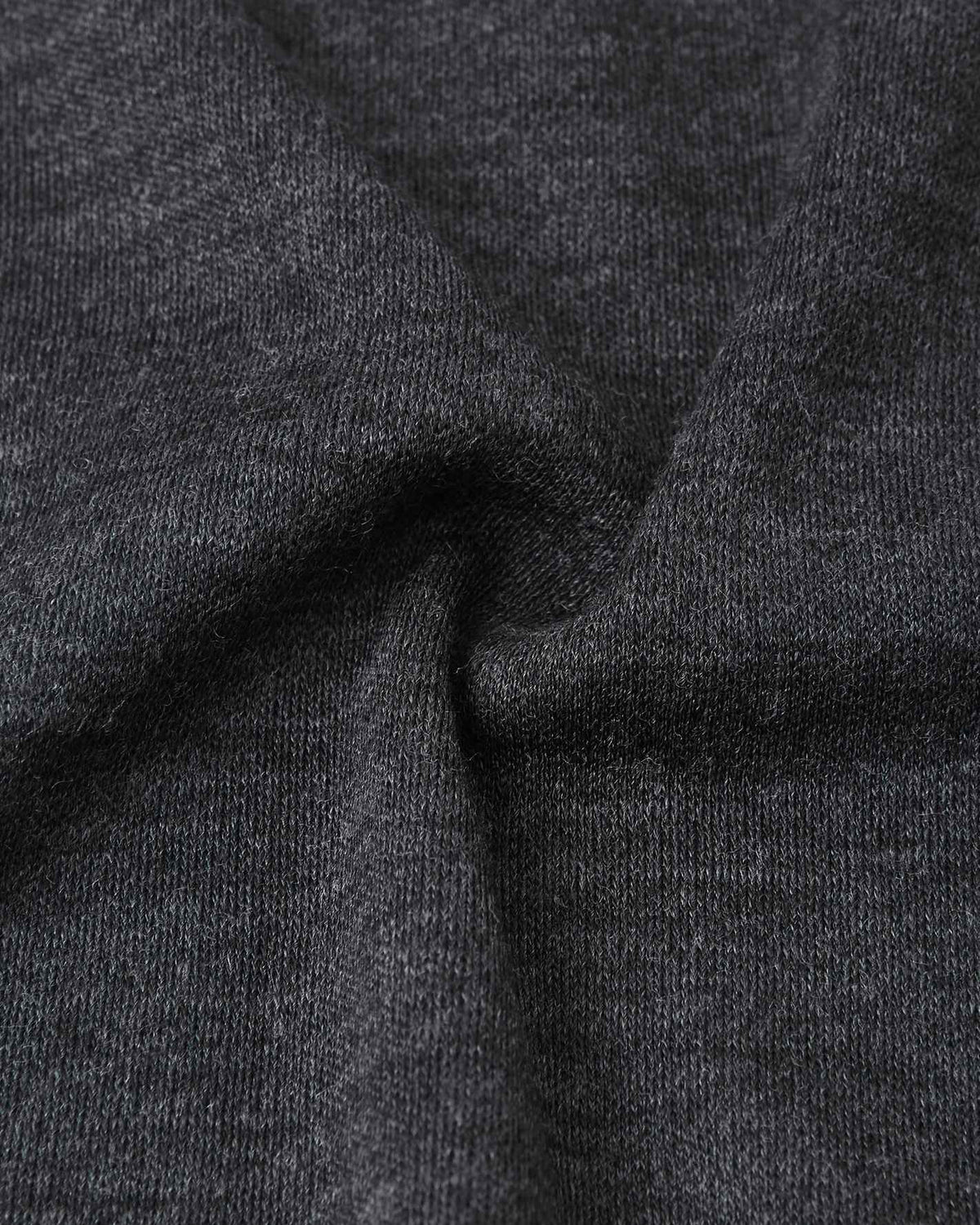 Macro close-up of the premium black melange wool knit fabric on the Reima Aurora kids' balaclava, highlighting the breathable, temperature-regulating base layer material.