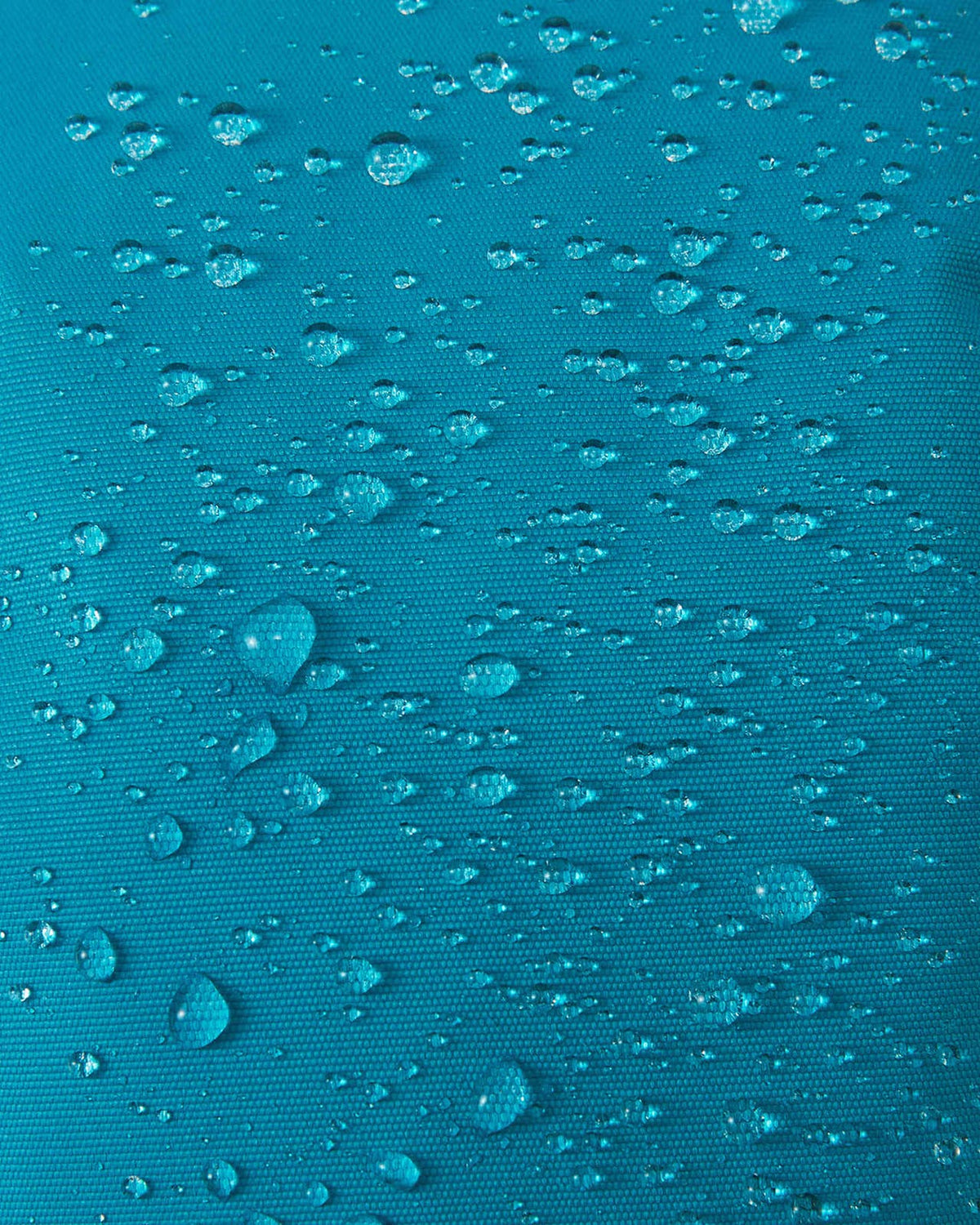 Macro shot of the aquatic blue fabric on the Reima Hankas kids' ski gloves, showing dense water droplets beading and rolling off the surface to prove waterproof and dirt-repellent durability.