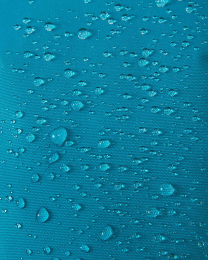 Macro shot of the aquatic blue fabric on the Reima Hankas kids' ski gloves, showing dense water droplets beading and rolling off the surface to prove waterproof and dirt-repellent durability.