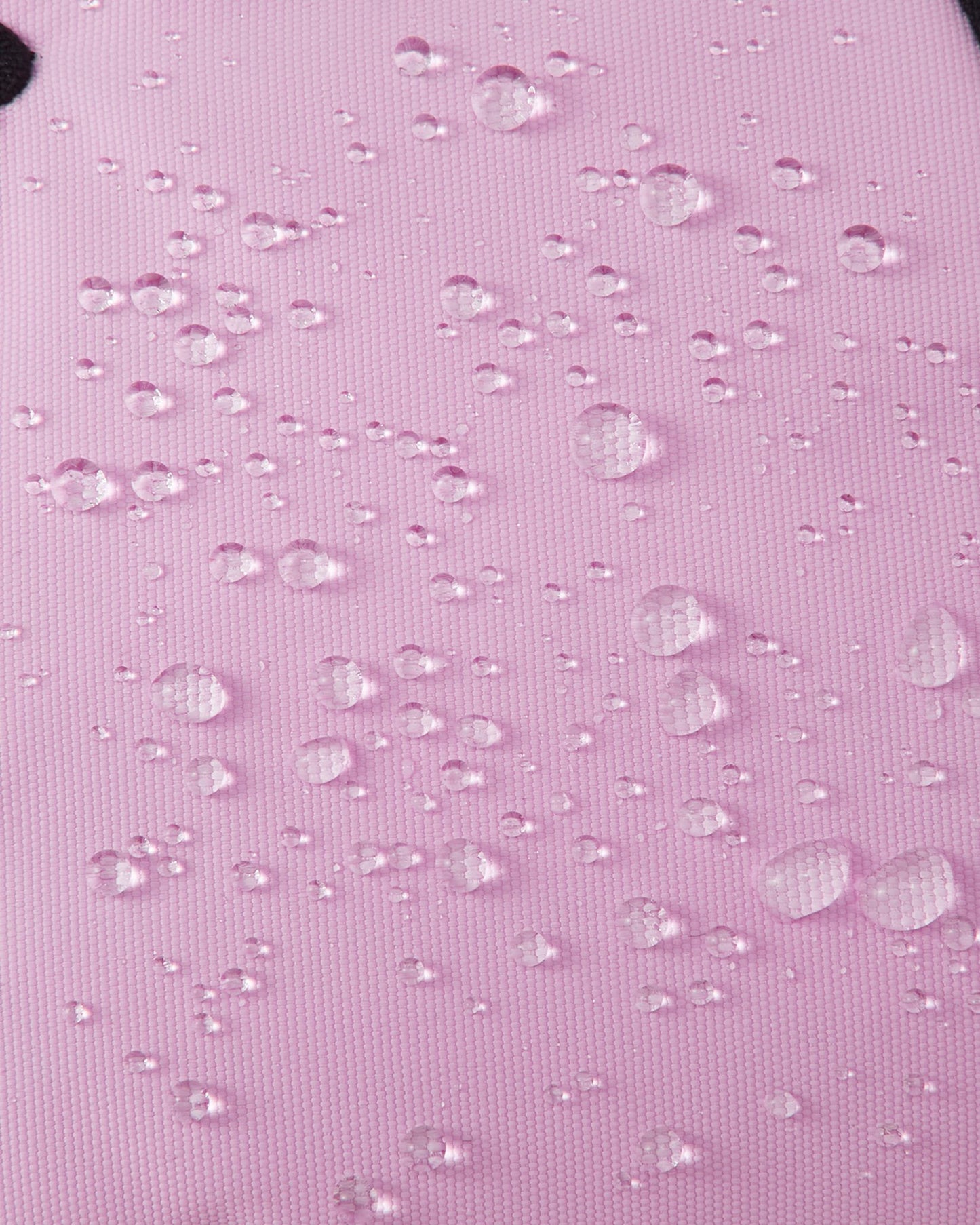 Macro texture shot of the light heather pink exterior fabric on Reima Hankas Reimatec kids ski gloves, with water droplets perfectly beading to showcase its highly waterproof finish.