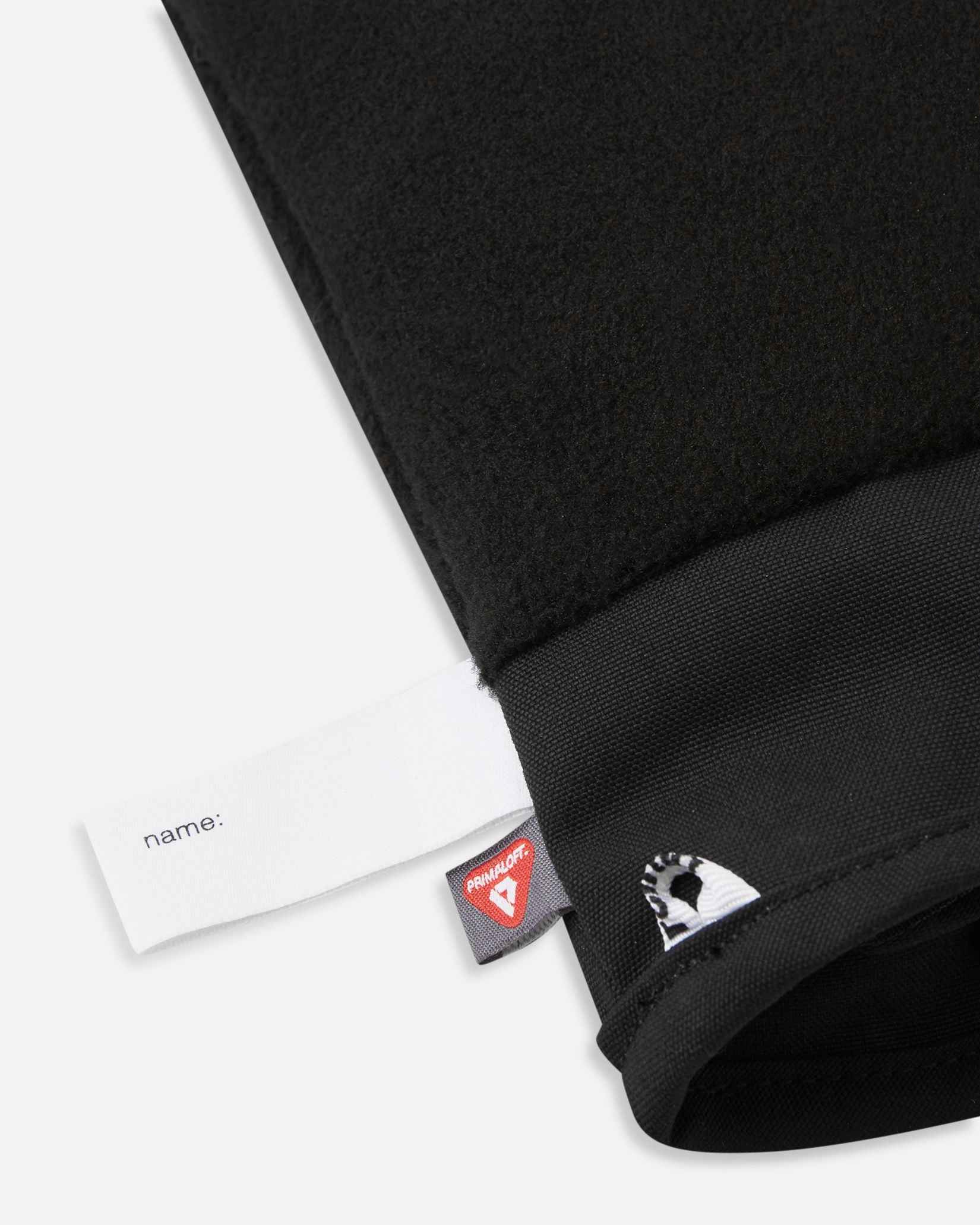 Detail of the inner cuff of the blooming lilac Reima Hanskas kids' ski gloves, showing the soft black fleece lining, a blank customizable name tag, and the premium PrimaLoft insulation tag for cold weather warmth.
