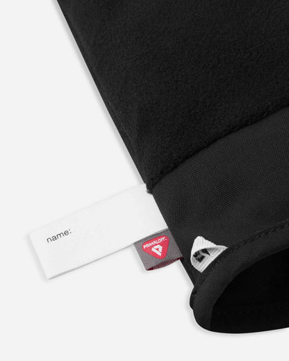 Detail of the inner cuff of the soft coral Reima Hanskas kids' ski gloves, showing the soft black thermal fleece lining, a customizable blank name tag, and the premium PrimaLoft insulation label indicating high-performance winter warmth.