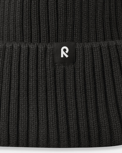 Macro close-up of the soft, breathable organic cotton ribbed knit fabric used on the black Reima Hattara kids' beanie.
