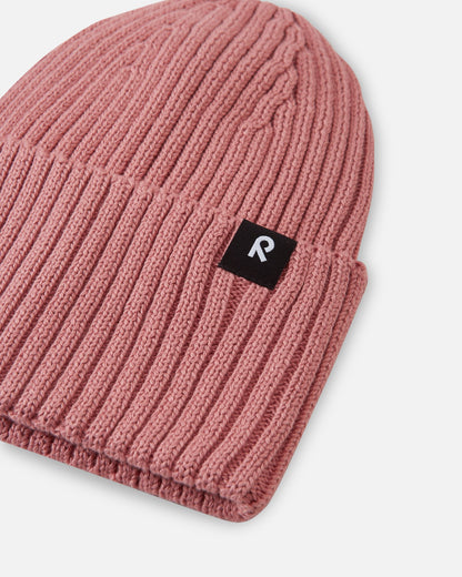 Close-up texture detail of the soft organic cotton knit on the rose blush Reima Hattara kids' beanie, showing the high-quality ribbed pattern and logo patch.
