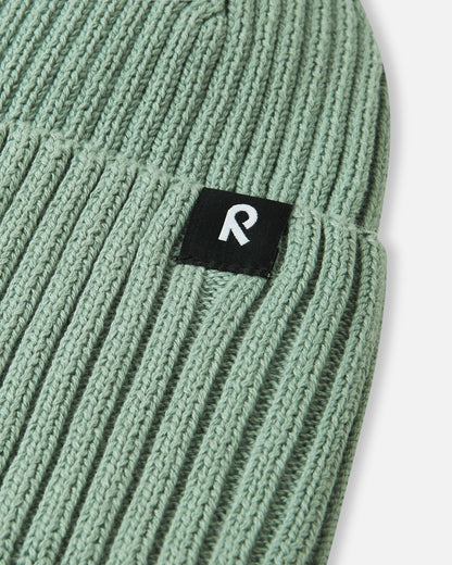 Macro close-up of the soft, breathable organic cotton ribbed knit fabric used on the stone green Reima Hattara kids' beanie.