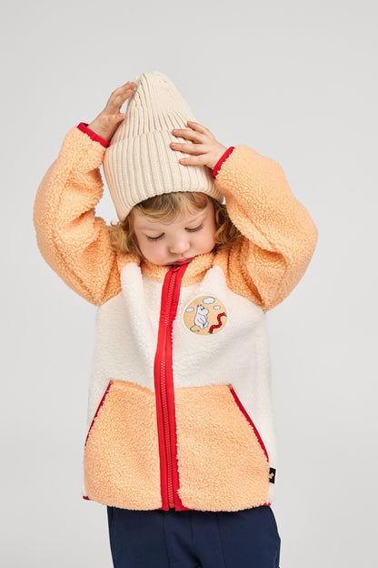 Lifestyle shot of a young child wearing the birch beige Reima Hattara kids' organic cotton beanie paired with a cozy sherpa fleece jacket, demonstrating its comfortable everyday fall wear fit.