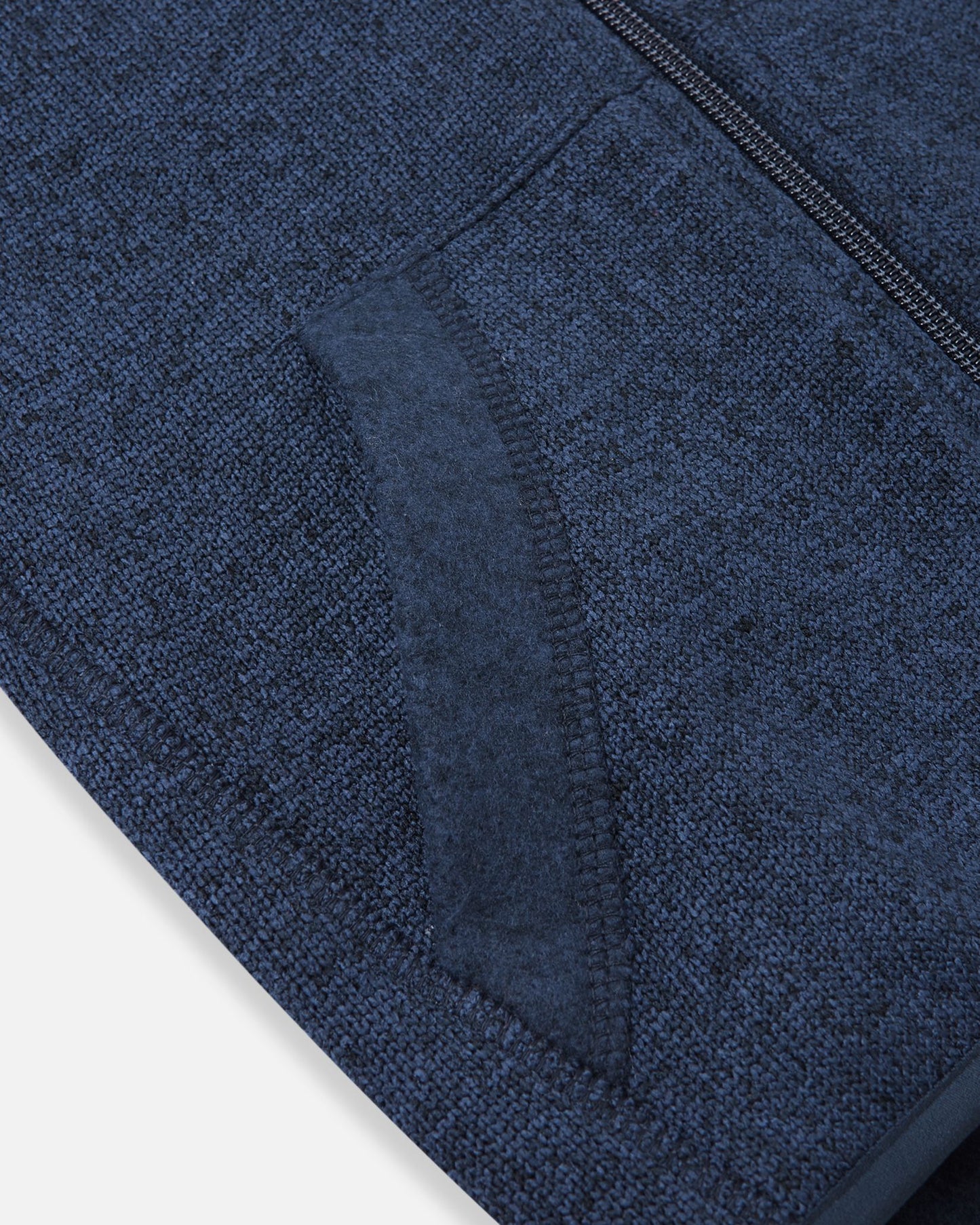 Detail view of the front handwarmer pocket on the Reima Hopper kids' jeans blue knit fleece jacket, featuring reinforced stitching for durability.