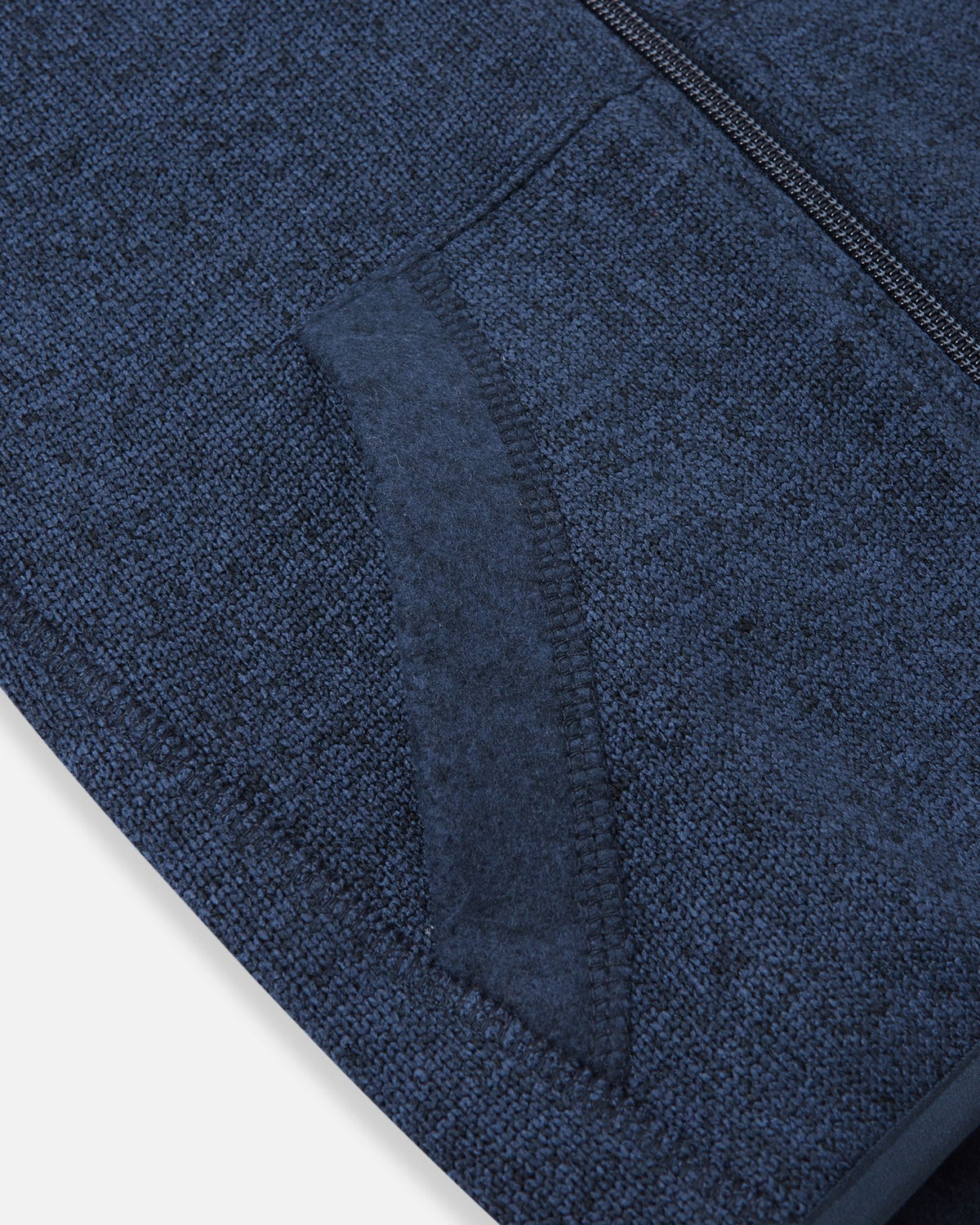 Detail view of the front handwarmer pocket on the Reima Hopper kids' jeans blue knit fleece jacket, featuring reinforced stitching for durability.