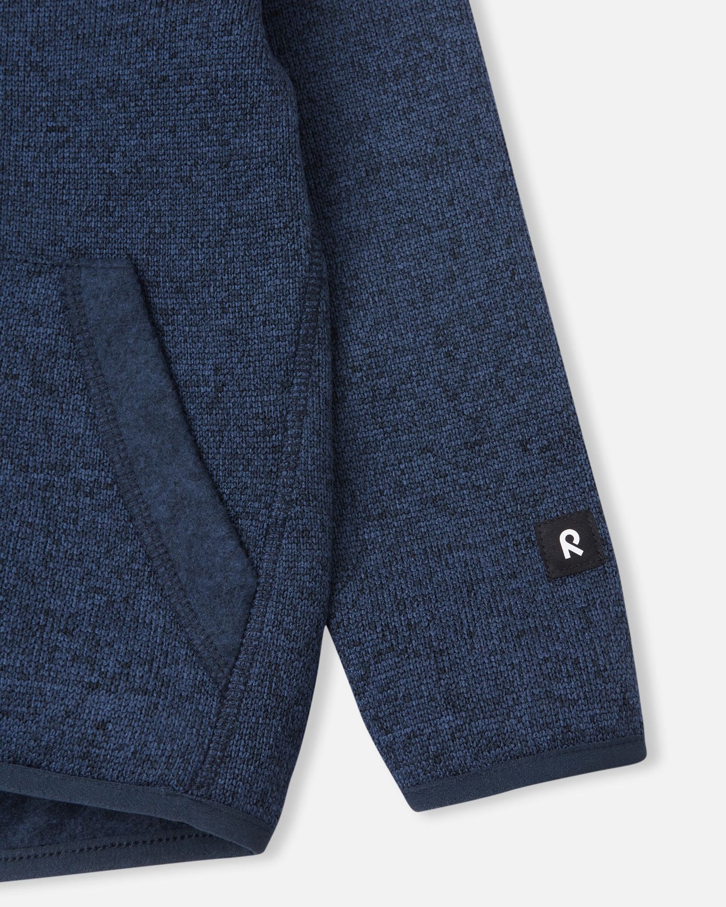 Close-up of the ribbed sleeve cuff and branded Reima logo patch on the jeans blue Reima Hopper kids' knit fleece jacket.