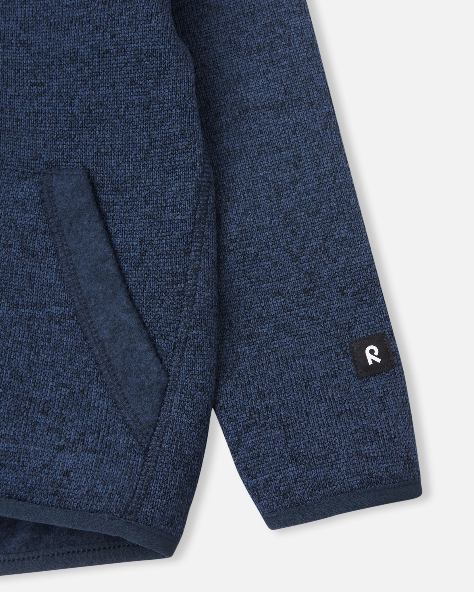 Close-up of the ribbed sleeve cuff and branded Reima logo patch on the jeans blue Reima Hopper kids' knit fleece jacket.