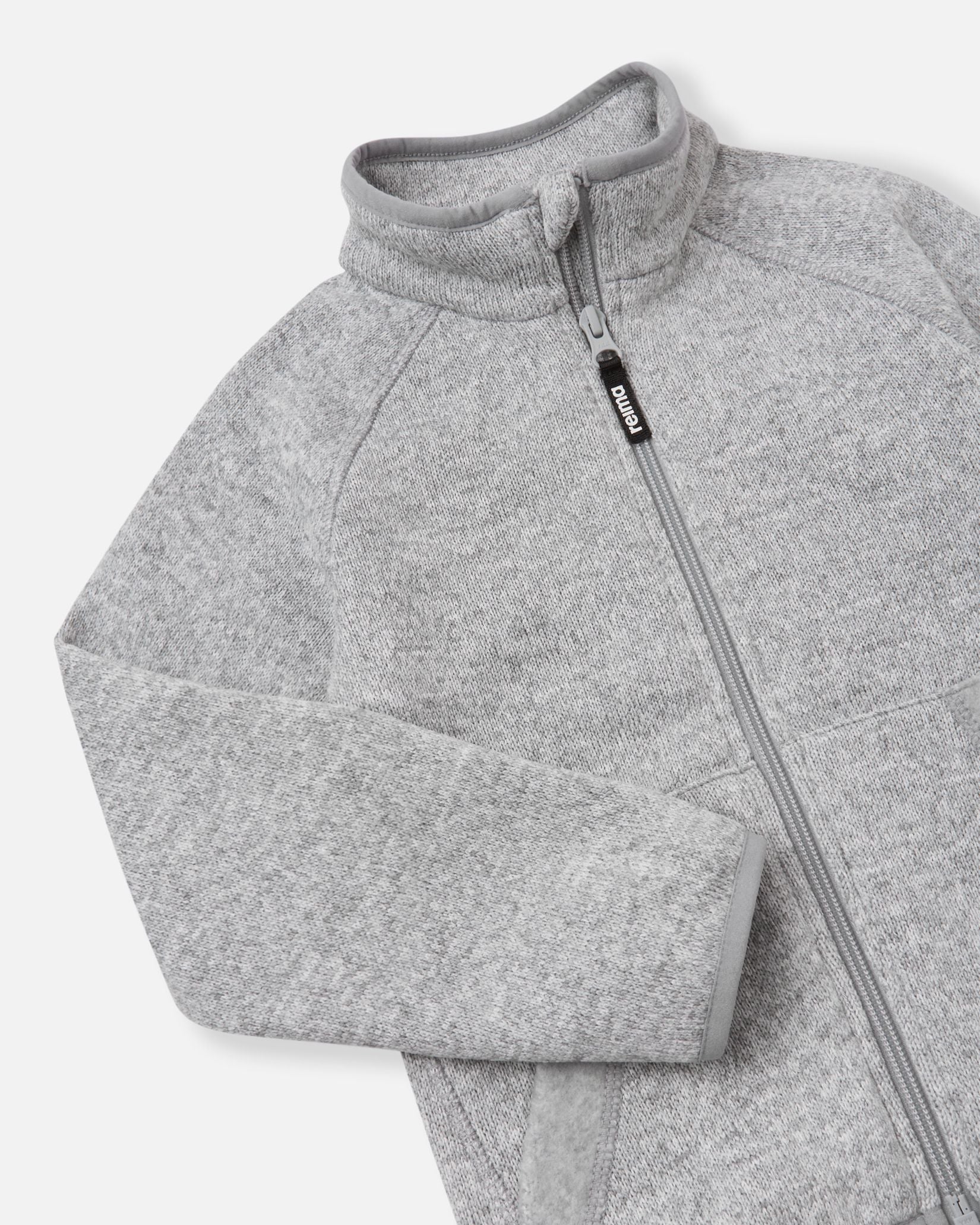 Close-up of the high collar and full-length zipper on the melange grey Reima Hopper kids' fleece jacket, highlighting the smooth zipper operation and anti-chafe chin guard design.