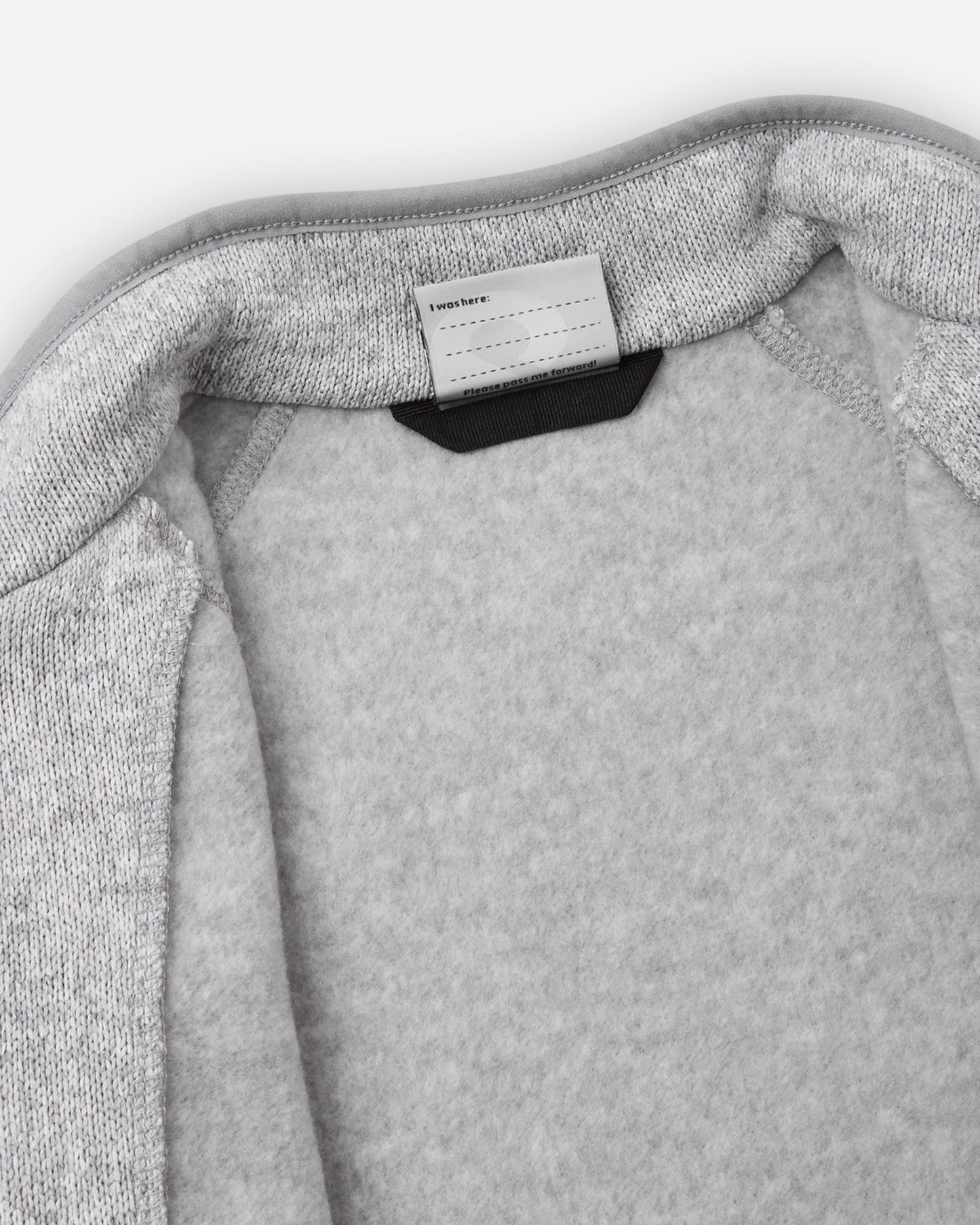 View of the inner neck label and writable name tag on the melange grey Reima Hopper kids' knit fleece jacket, showcasing the soft brushed fleece interior lining.