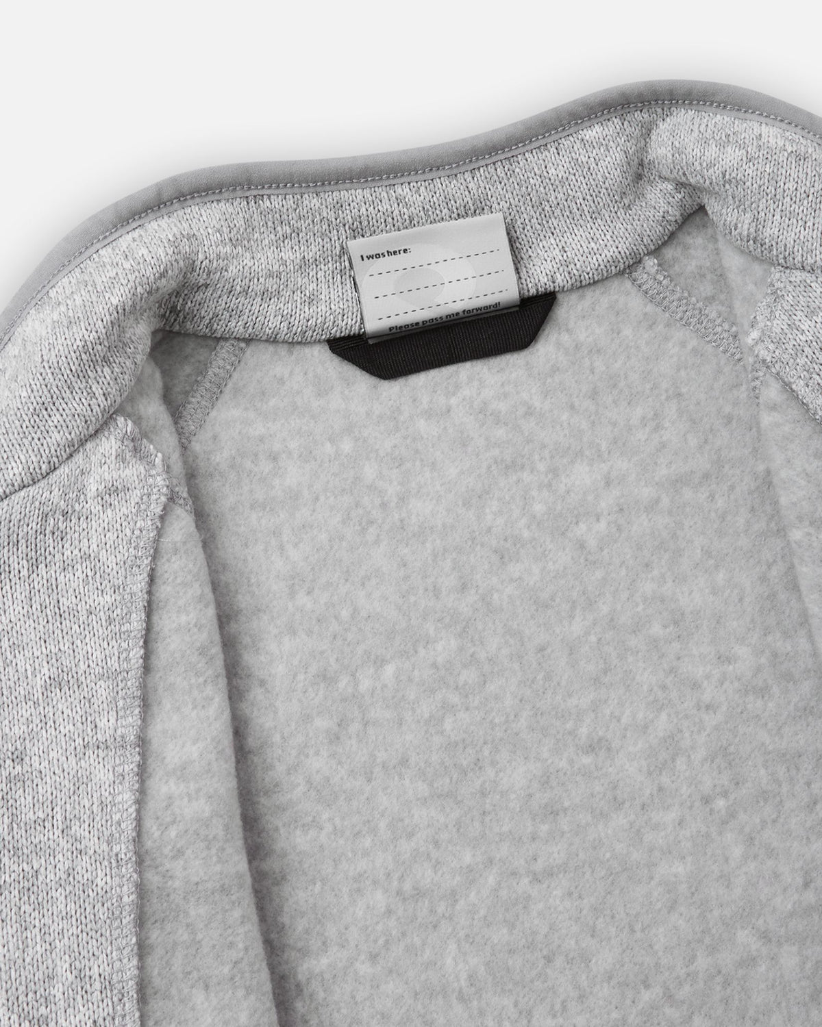 View of the inner neck label and writable name tag on the melange grey Reima Hopper kids' knit fleece jacket, showcasing the soft brushed fleece interior lining.