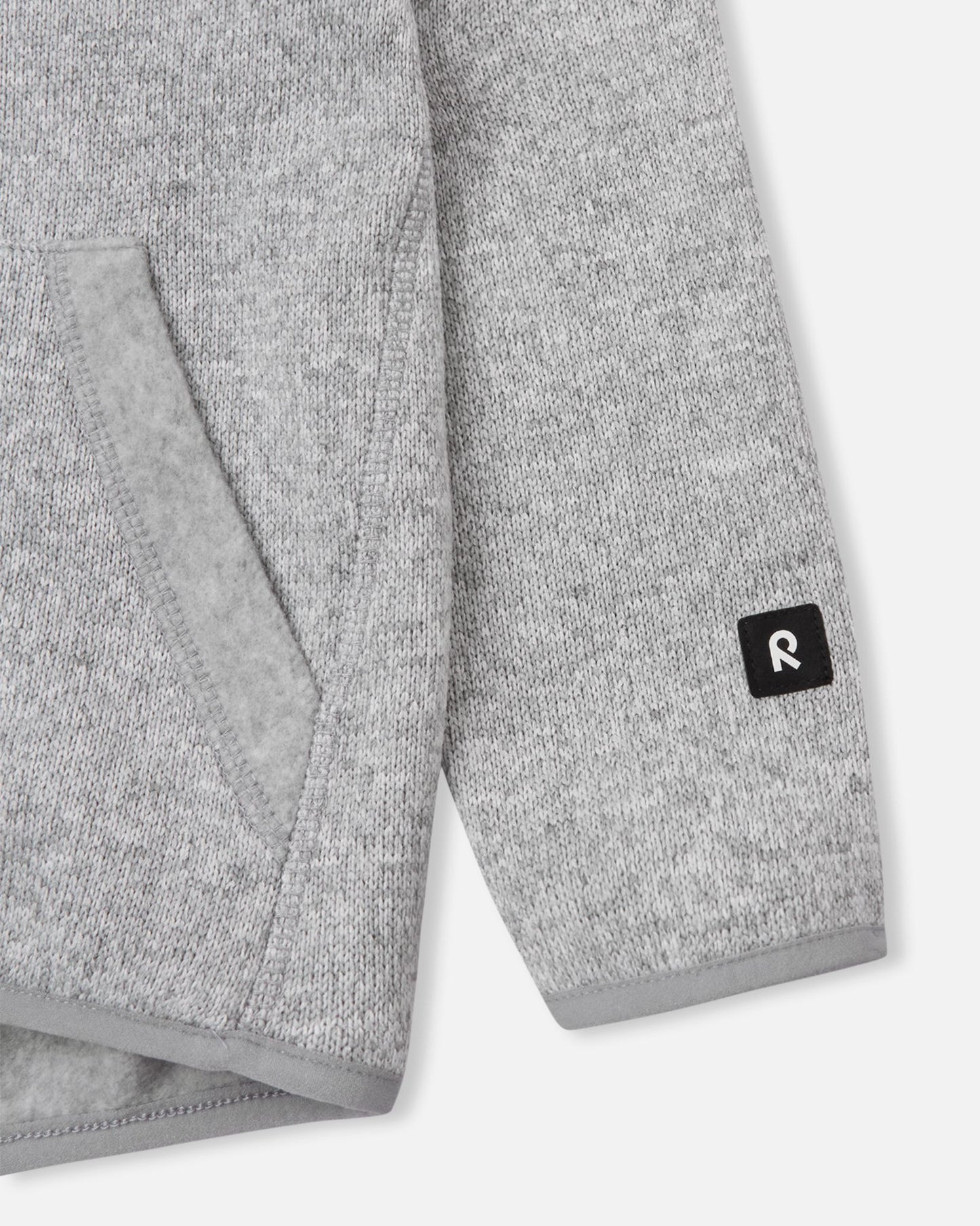 Close-up of the ribbed sleeve cuff and branded black Reima logo patch on the melange grey Reima Hopper kids' knit fleece jacket.
