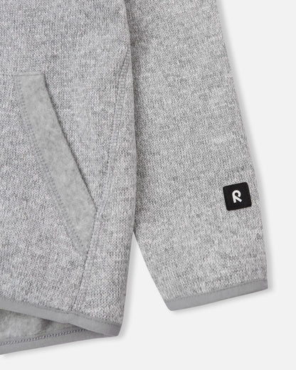 Close-up of the ribbed sleeve cuff and branded black Reima logo patch on the melange grey Reima Hopper kids' knit fleece jacket.