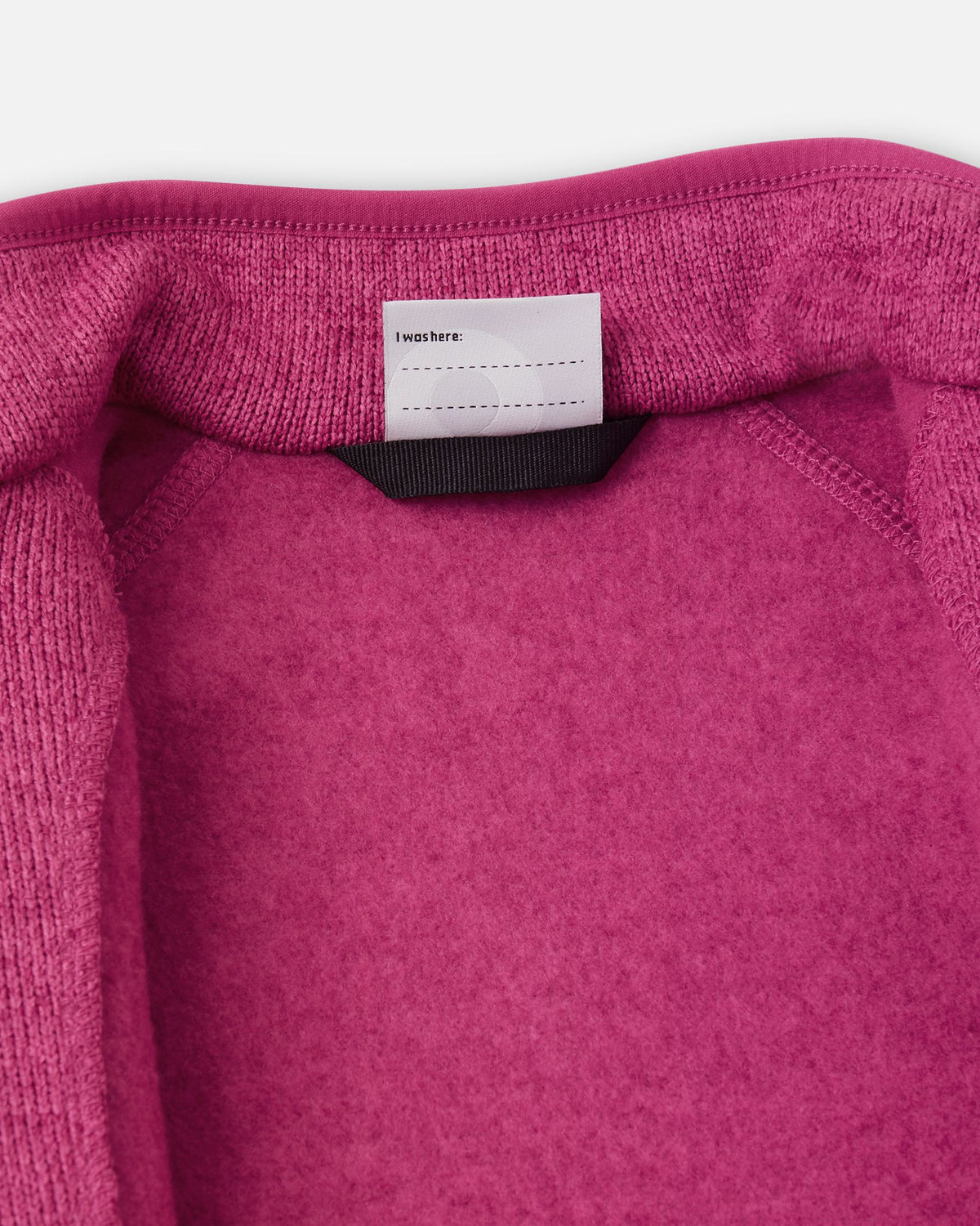 View of the inner neck label and writable name tag on the rosy berry Reima Hopper kids' knit fleece jacket, showcasing the soft brushed fleece interior.