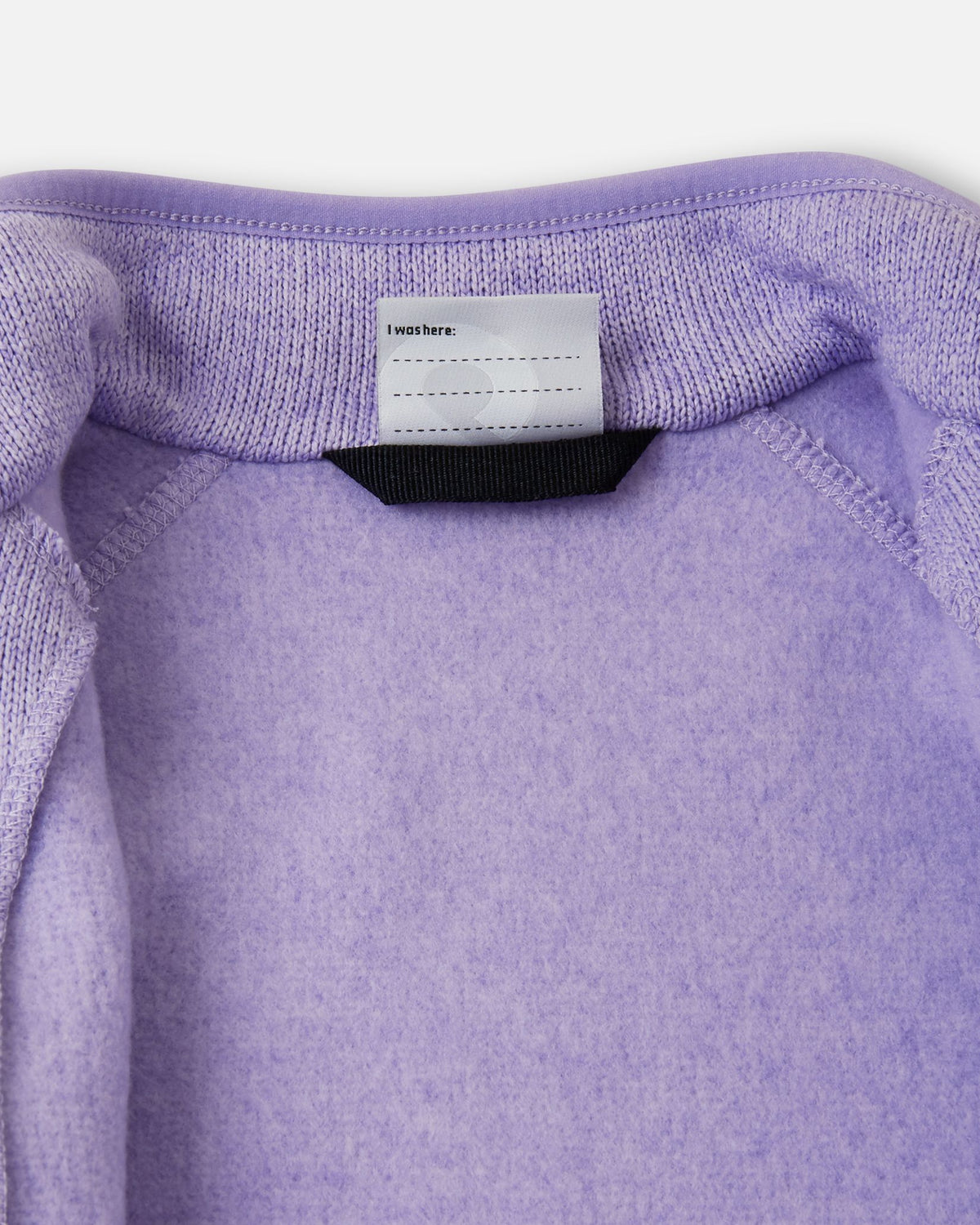 View of the inner neck label and writable name tag on the blooming lilac Reima Hopper kids' knit fleece jacket, showcasing the soft brushed fleece interior.