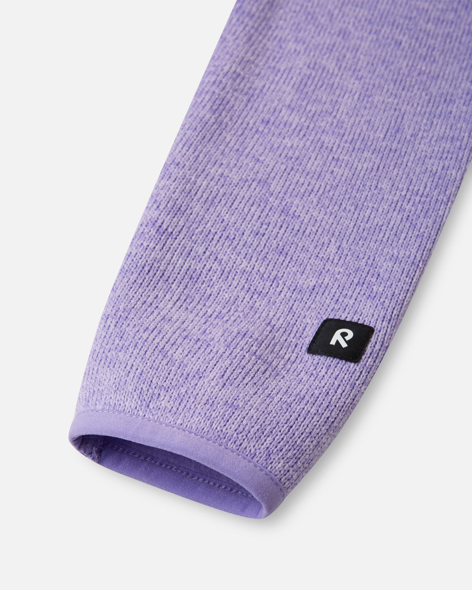 Close-up of the bound sleeve cuff and branded Reima logo patch on the blooming lilac Reima Hopper kids' knit fleece jacket.