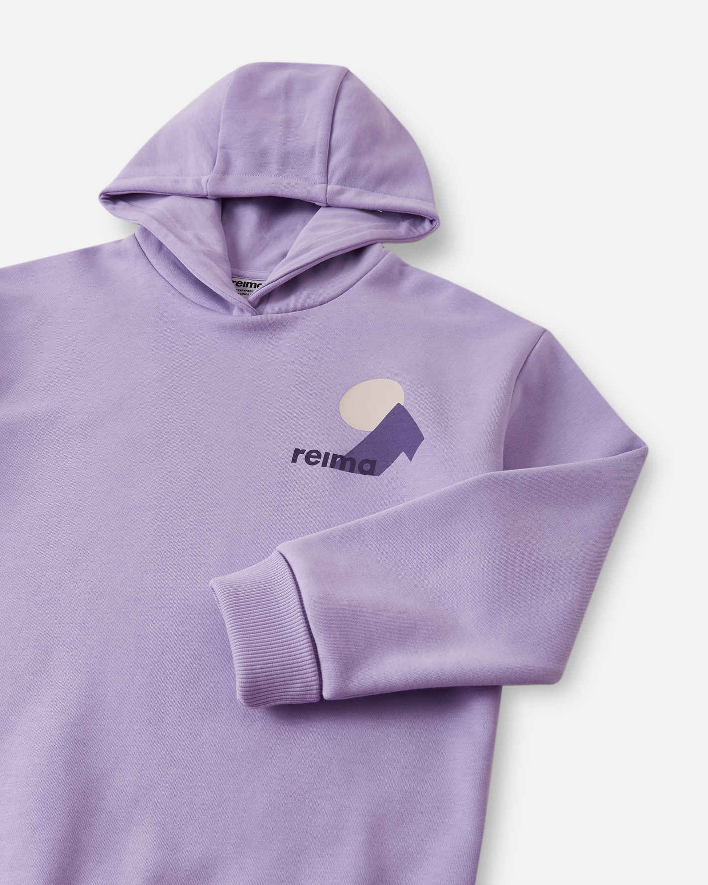 Close-up detail of the blooming lilac Reima Huppis kids' hoodie, highlighting the smooth organic cotton knit fabric and the subtle geometric mountain and setting sun graphic printed on the chest.
