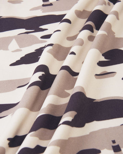 Macro close-up of the high-quality, smooth fleece material on the earthy beige Reima Iisisti kids' jacket, showcasing the neutral grey and tan tones of the distinctive sailboat camo print.