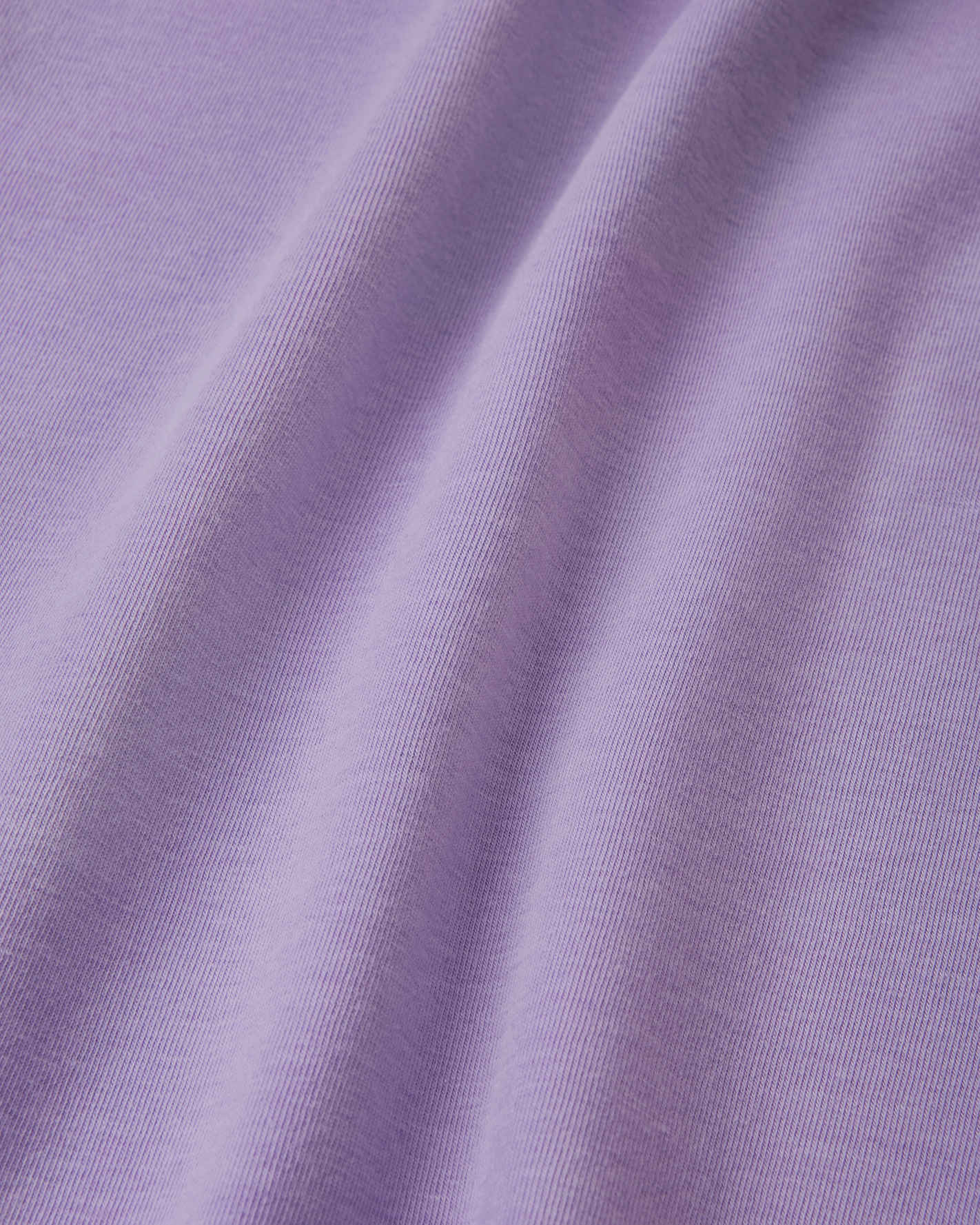 Close-up detail of the smooth, blooming lilac UPF 50+ fabric on the Reima Ikioma kids' summer t-shirt, showing the breathable knit structure that provides lasting comfort and UV protection.