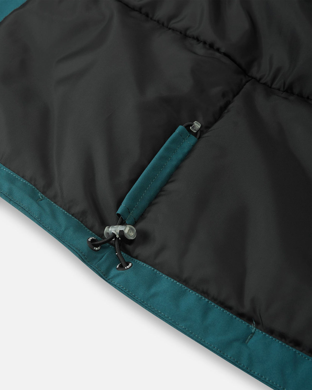 Detail of the interior adjustable hem on the dark teal Reima Jatuni kids' ski jacket, showing the elastic bungee cord and toggle system for a secure, draft-blocking custom fit.