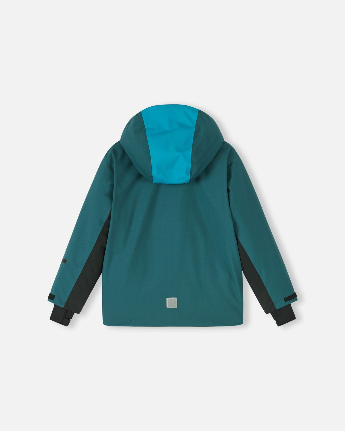 Back flat lay view of the dark teal Reima Jatuni kids' winter ski jacket, showcasing the color-blocked detachable hood, adjustable black sleeve cuffs, and a lower-back safety reflective Reima logo for visibility.