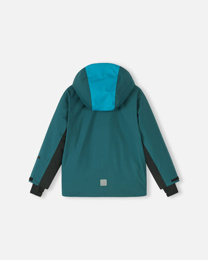 Back flat lay view of the dark teal Reima Jatuni kids' winter ski jacket, showcasing the color-blocked detachable hood, adjustable black sleeve cuffs, and a lower-back safety reflective Reima logo for visibility.