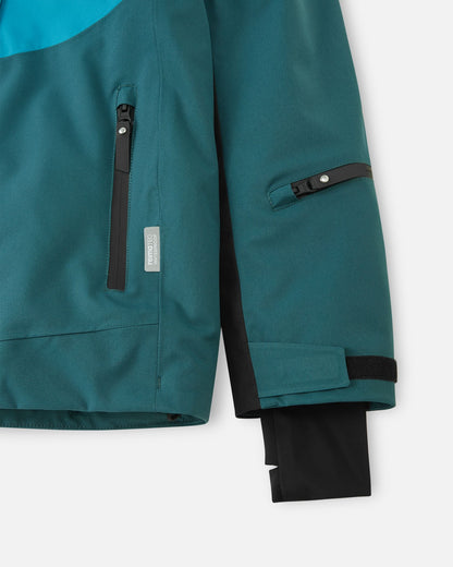 Detail of the sleeve on the dark teal Reima Jatuni kids' ski jacket, highlighting the zippered ski pass pocket on the forearm, an adjustable hook-and-loop cuff, and a stretchy inner Lycra cuff with a thumbhole to lock out the cold.
