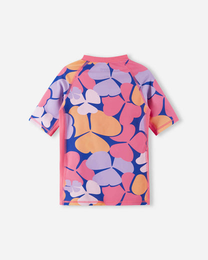 Back view of the soft coral Reima Joonia girls' UPF 50+ swim shirt, featuring a vibrant floral pattern on the body and contrasting solid pink raglan sleeves for an athletic, comfortable summer fit.