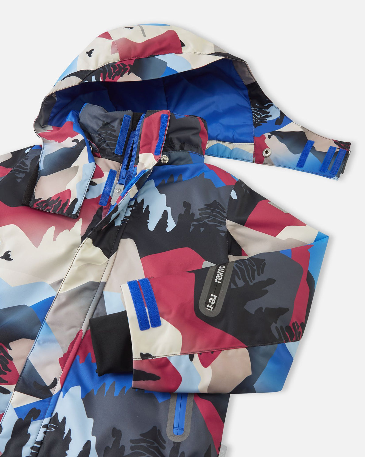 Close-up of the upper chest and collar on the Reima Kairala kids' ski jacket, detailing the snap buttons for the detachable safety hood, the main protective zipper, and the left sleeve ski pass pocket.