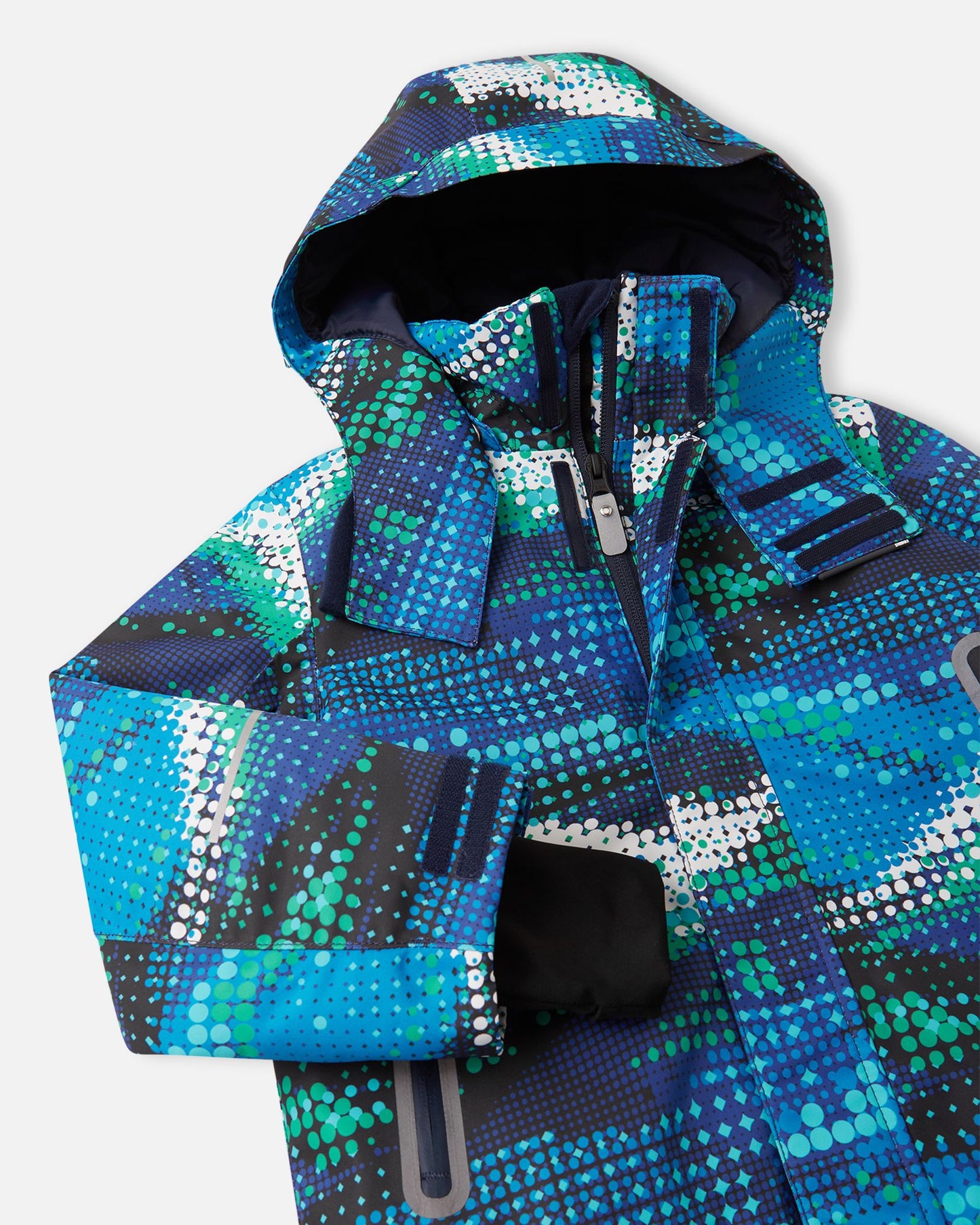 Close-up detail of the twilight blue Reima Kairala kids' waterproof ski jacket, highlighting the durable sealed main zipper, high protective collar, and dynamic digital dot design.