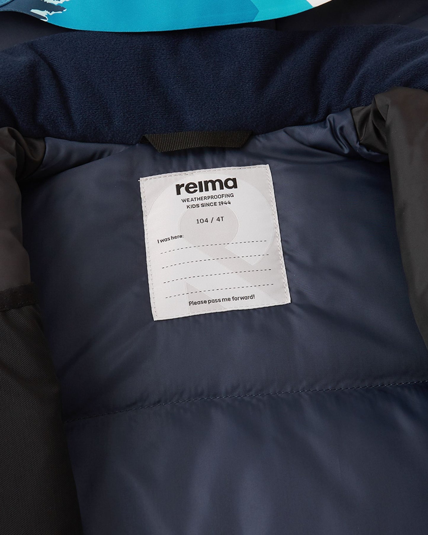 Close-up of the interior Reima name tag sewn into the smooth winter lining of the bright blue Kairala kids' waterproof ski jacket.