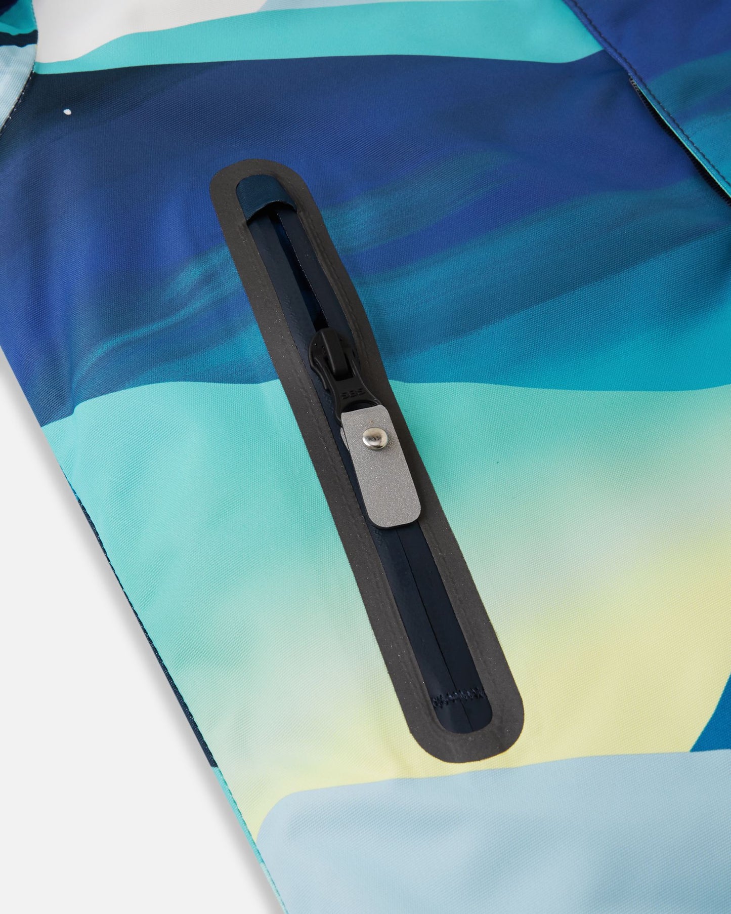 Close-up of the sealed, water-resistant zipper pocket on the front panel of the bright blue Reima Kairala kids' winter ski jacket, showcasing the durable construction.