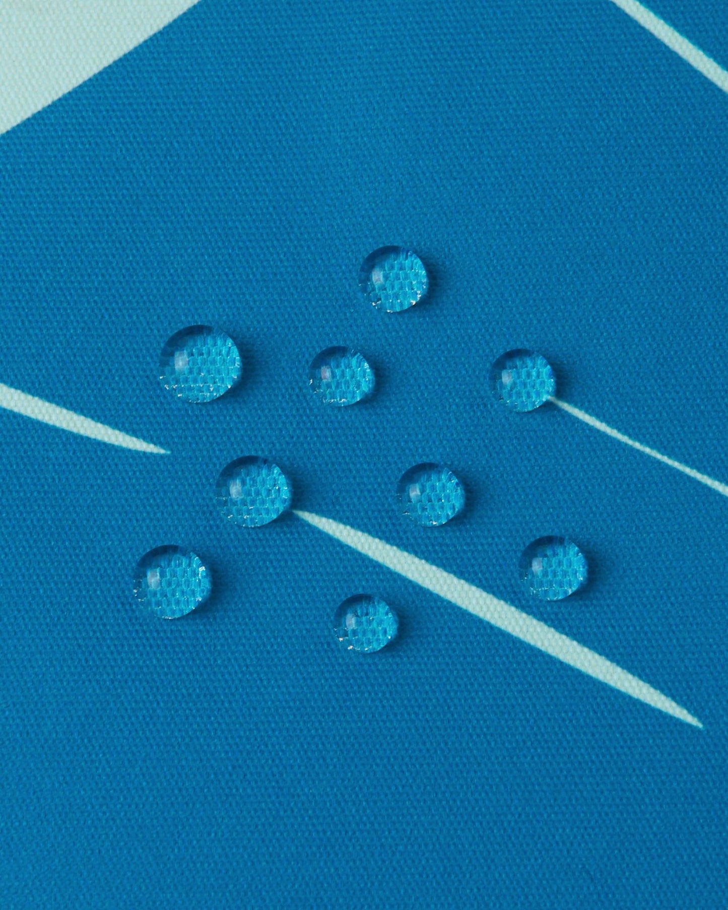Macro shot demonstrating the water-repellent shell of the bright blue Reima Kairala toddler snow coat, with moisture perfectly beading to keep kids dry on the slopes.