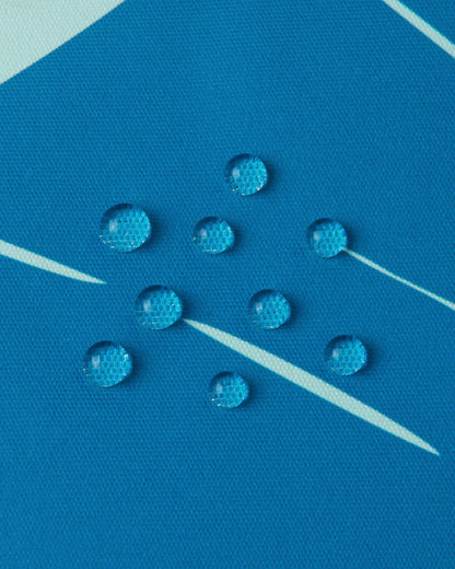 Macro shot demonstrating the water-repellent shell of the bright blue Reima Kairala toddler snow coat, with moisture perfectly beading to keep kids dry on the slopes.