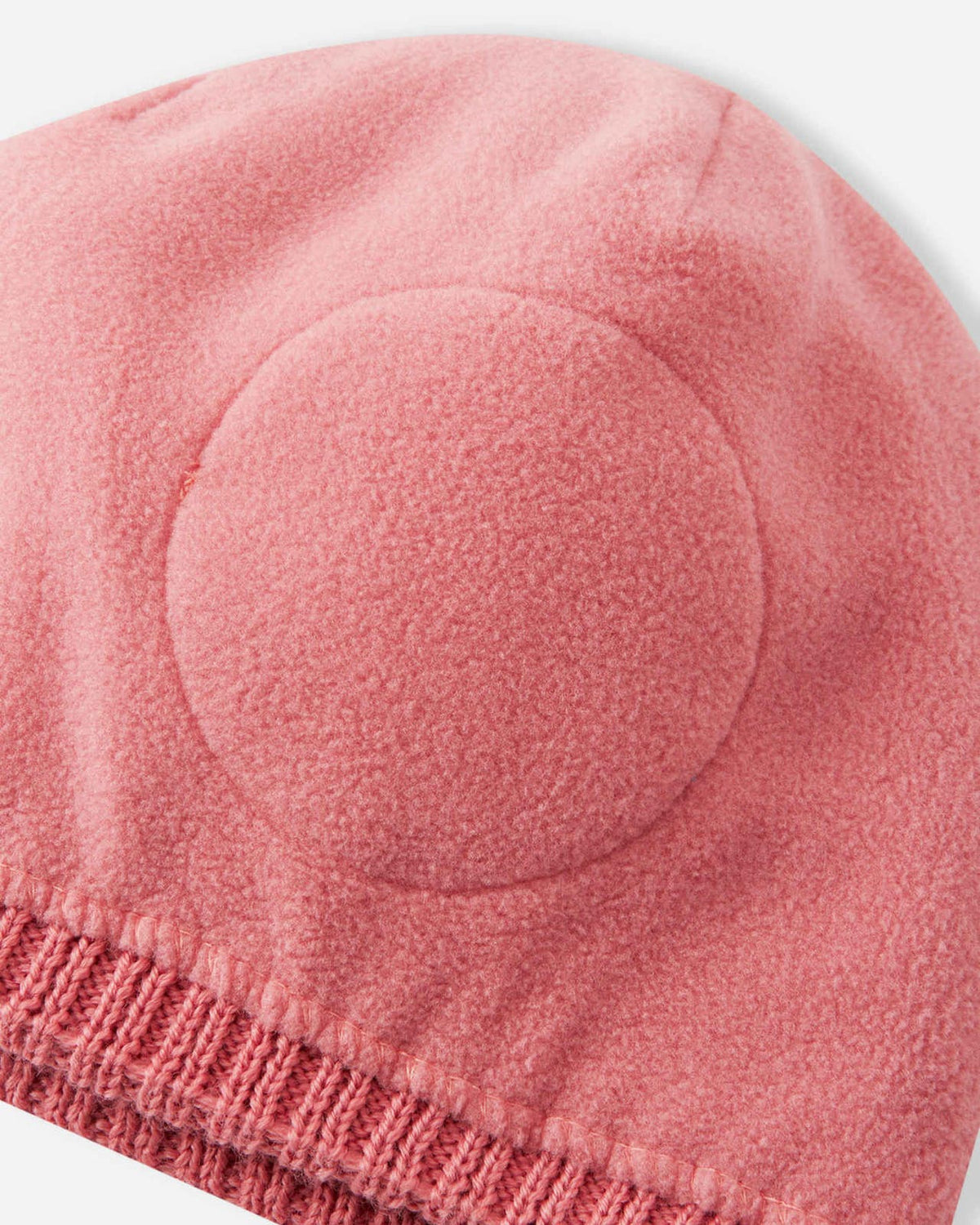 Interior close-up of the Reima Kalotti kids' winter beanie in rose blush, displaying the warm inner fleece lining and the built-in circular windproof earpieces designed to protect against cold winter winds.